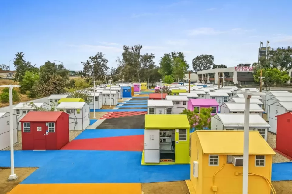 Multicolored tiny homes for temporary shelter in complex adjacent to freeway overpass in Los Angeles, California.